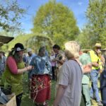 Besucher:innen beim Pflanzenmarkt im Wangeliner Garten 2025 bei Sonnenschein. Verkauf von Tomatenpflanzen und regionalem Kunsthandwerk.